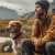 A man and his dog walking together on a scenic outdoor trail surrounded by trees and nature